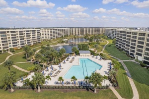Large community swimming pool in Siesta Key Florida with a sun deck lounge chairs and tropical landscaping.