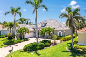 Professional aerial photography Realty Media 360 of a modern luxury home in Englewood Florida featuring a tile roof, manicured tropical landscaping, and tall palm trees.