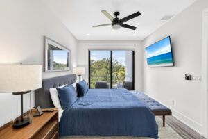 Modern luxury primary bedroom in Sarasota featuring a private balcony view and professional interior lighting.