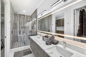 Modern Sarasota primary bathroom featuring a monolithic stone basin and an expansive halo backlit smart mirror with a soft ambient glow.