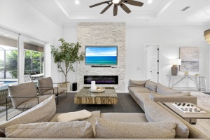Professional interior photo of a modern living room featuring a custom stone fireplace, large sectional sofa, and recessed lighting. Done by Realty Media 360 in Cape Coral Florida.