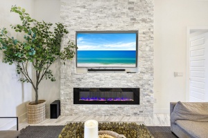 Professional interior photo of a floor-to-ceiling white stone fireplace with a modern electric insert and mounted television in a luxury home. Done by Realty Media 360 in Cape Coral Florida.
