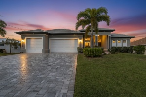 Professional twilight real estate photography by Realty Media 360 of a modern single-family home with a paved driveway and palm trees in Florida.
