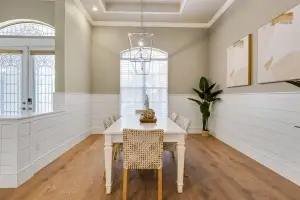 Interior view by Realty Media 360 of a bright, modern kitchen with white cabinets, high-end built-in ovens, and a spacious open layout leading into the living area.