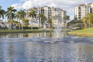 Front exterior view of Court of Palms Condos in Fort Myers, Florida, featuring a decorative tiered water fountain and lush tropical landscaping.